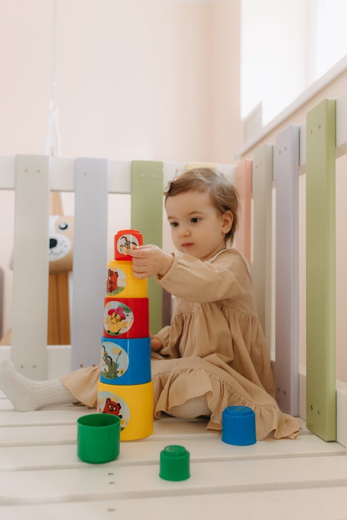 A toddler playing with a toy tower in a crib